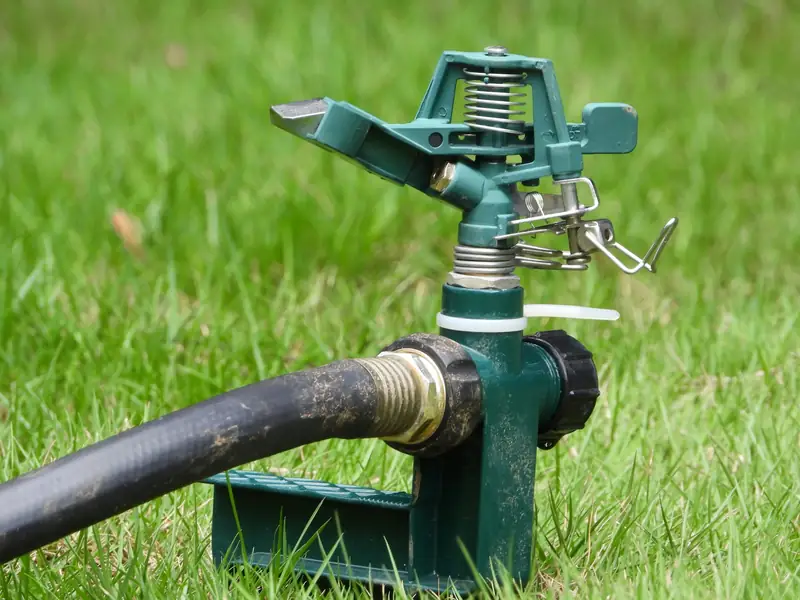 Close-up of a metal impact rotor sprinkler head on a lawn