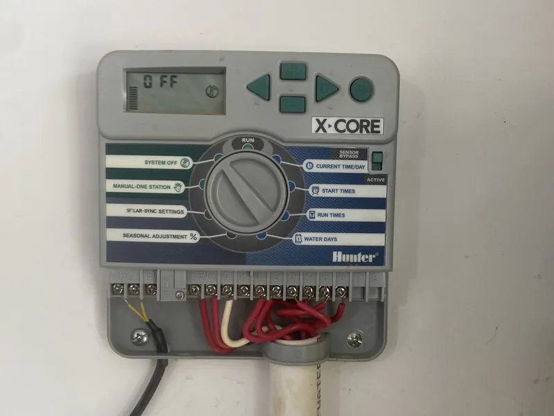 Hunter X-Core sprinkler controller showing OFF on its display, with red zone wires connected to its terminal strip