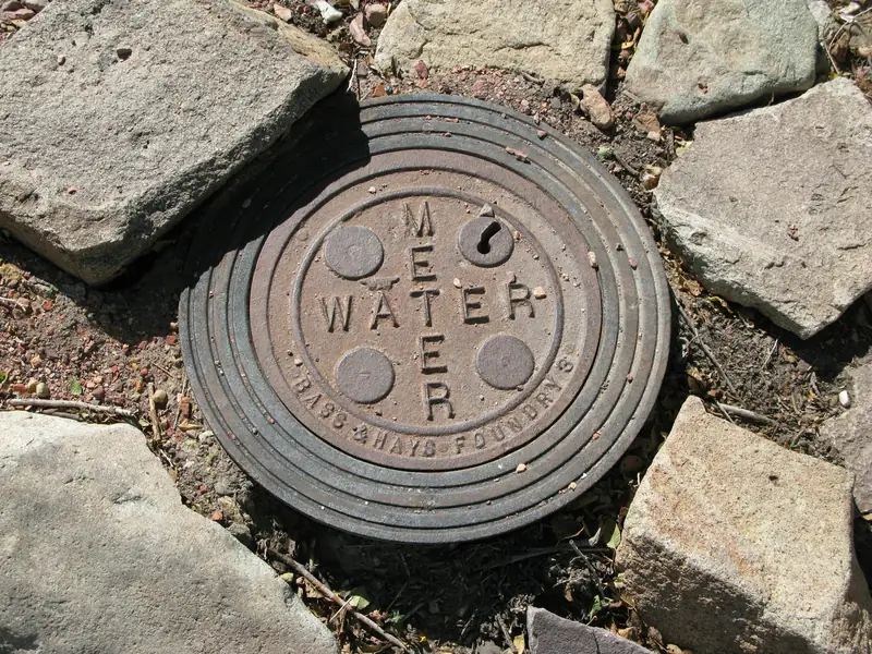 Cast-iron water meter cover set in the ground among stones